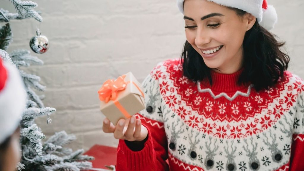 woman in sweater and santa hat with gift