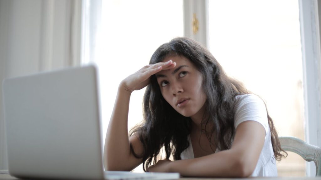 young woman sitting in front of computer looking confused